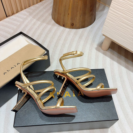 ALAIA THREE-STRAPS HIGH HEEL SANDALS IN GOLDEN PATENT LAMBSKIN