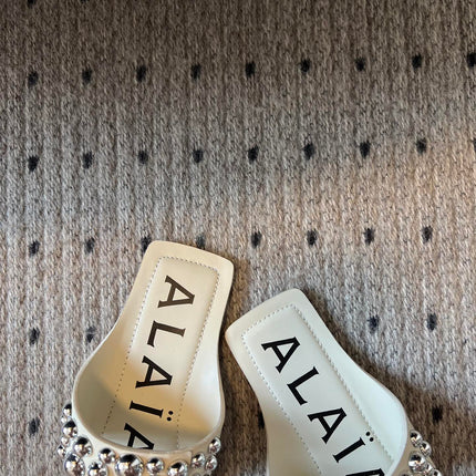 ALAIA FOLDED FLAT MULES WITH SPHERES ON WHITE CALFSKIN