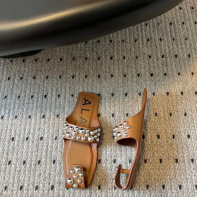 ALAIA FOLDED FLAT MULES WITH SPHERES ON COPPER BROWN CALFSKIN