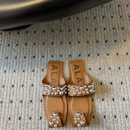 ALAIA FOLDED FLAT MULES WITH SPHERES ON COPPER BROWN CALFSKIN